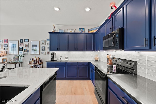 kitchen featuring black appliances, tasteful backsplash, blue cabinetry, and light hardwood / wood-style flooring