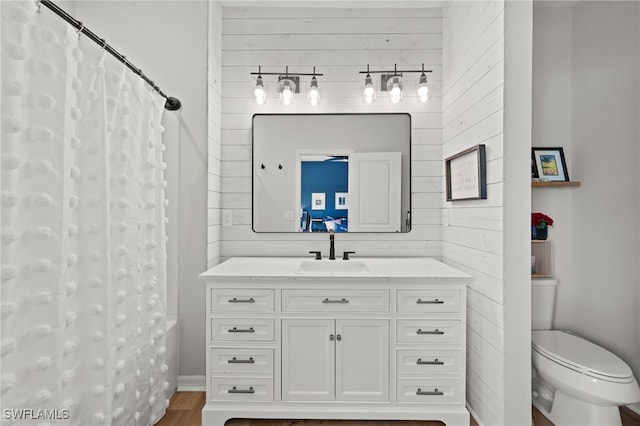 full bathroom with shower / bath combo, hardwood / wood-style flooring, wooden walls, vanity, and toilet