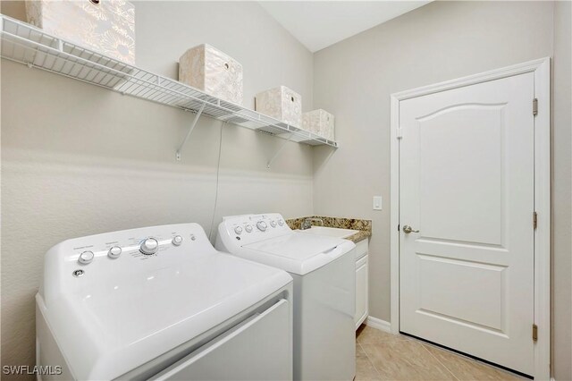 laundry room with light tile patterned floors, sink, independent washer and dryer, and cabinets