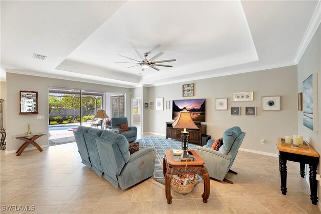 tiled living room featuring a tray ceiling, ceiling fan, and crown molding