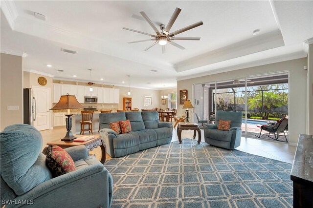 tiled living room featuring ornamental molding, a tray ceiling, and ceiling fan