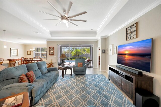 living room featuring ceiling fan, a tray ceiling, and crown molding