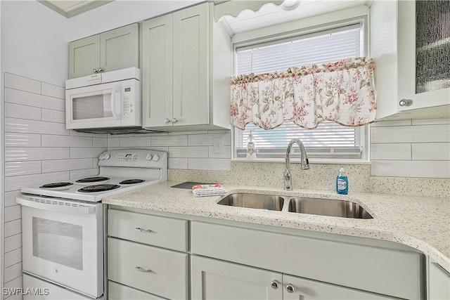 kitchen featuring decorative backsplash, light stone countertops, white appliances, and sink