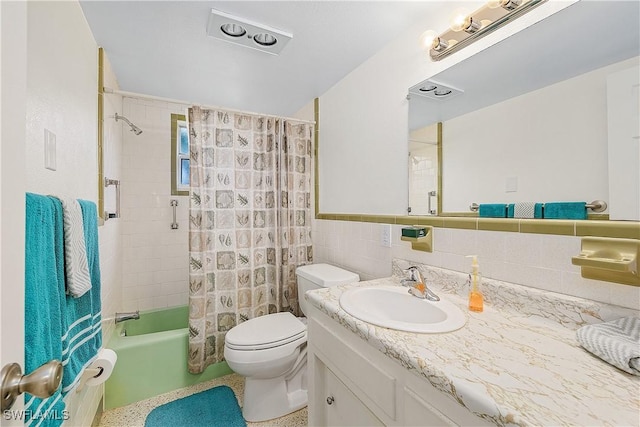 full bathroom with tiled shower / bath, vanity, tile walls, and toilet