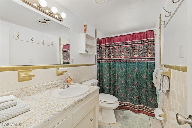 bathroom featuring tile patterned floors, vanity, tile walls, and toilet