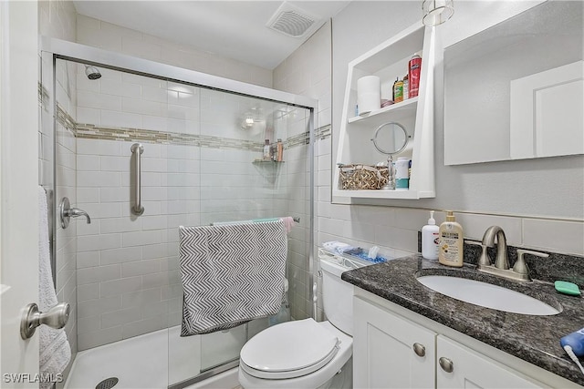 bathroom with an enclosed shower, vanity, toilet, and backsplash