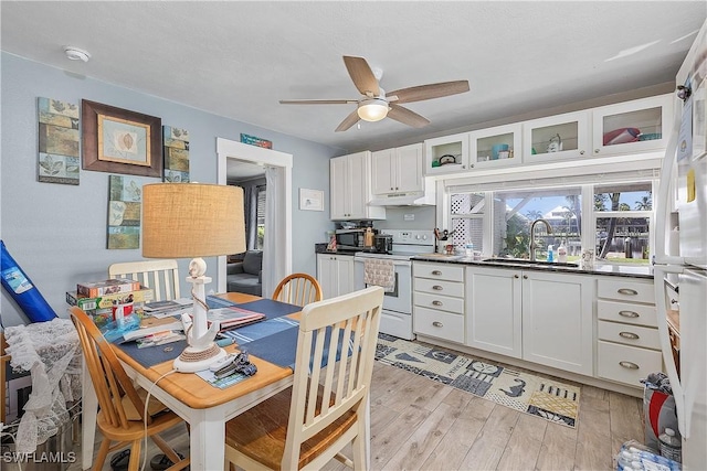 kitchen featuring white appliances, white cabinets, sink, light hardwood / wood-style flooring, and ceiling fan