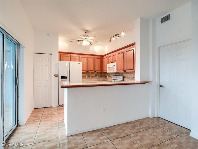 kitchen featuring kitchen peninsula, light tile patterned floors, white appliances, and tasteful backsplash