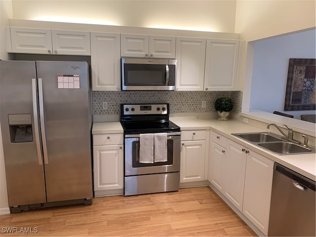 kitchen featuring stainless steel appliances, white cabinetry, sink, backsplash, and light wood-type flooring