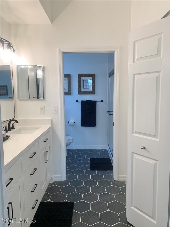 bathroom with toilet, vanity, and tile patterned floors