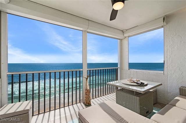 sunroom / solarium with a water view, a view of the beach, and ceiling fan