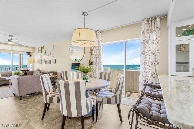 dining room featuring a water view, ceiling fan, and light parquet flooring