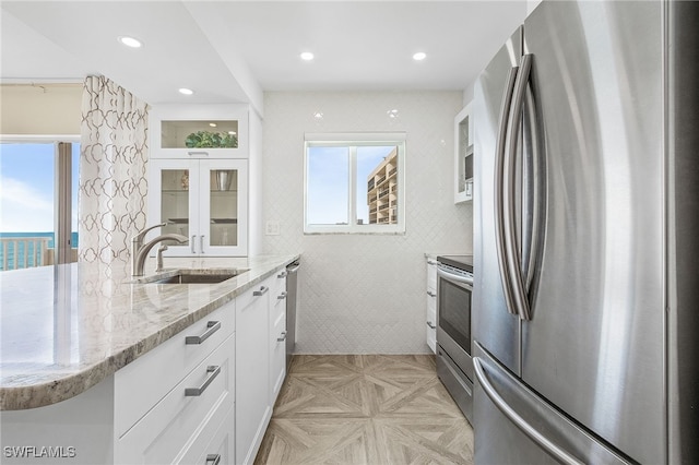 kitchen featuring white cabinetry, stainless steel appliances, and a wealth of natural light