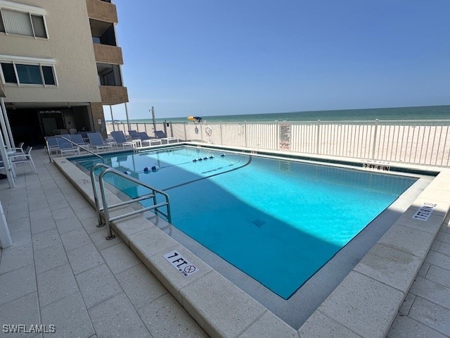 view of pool with a water view and a beach view