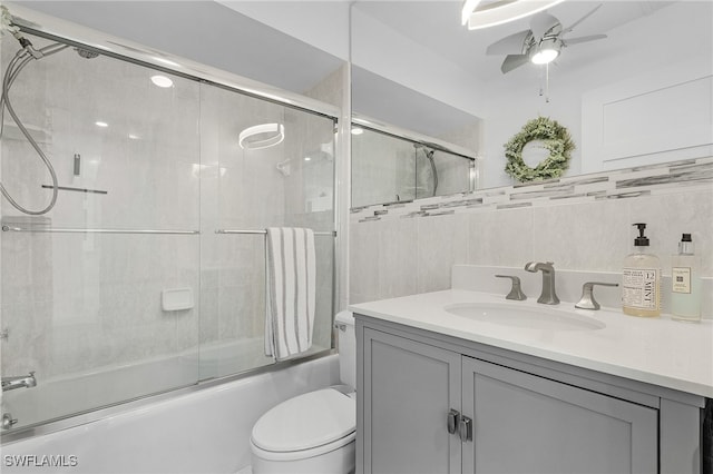 full bathroom featuring toilet, vanity, tile walls, combined bath / shower with glass door, and ceiling fan