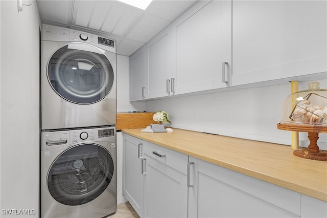 laundry area with cabinets and stacked washing maching and dryer