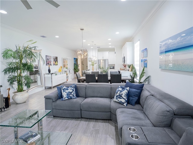 living room featuring light hardwood / wood-style flooring, ceiling fan with notable chandelier, and ornamental molding