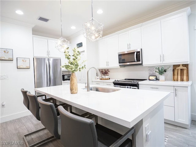 kitchen with a kitchen island with sink, stainless steel appliances, sink, and a kitchen breakfast bar