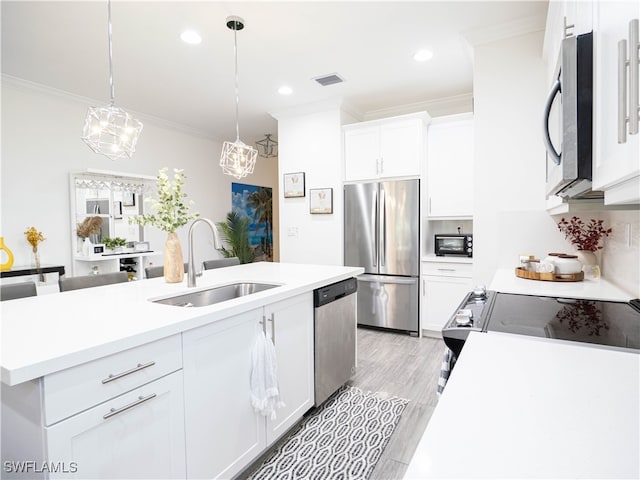 kitchen featuring appliances with stainless steel finishes, white cabinetry, pendant lighting, crown molding, and sink