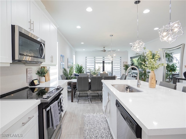 kitchen featuring appliances with stainless steel finishes, a center island with sink, and white cabinetry