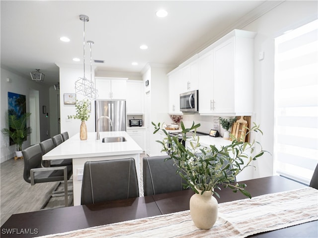 dining space featuring ornamental molding, hardwood / wood-style flooring, and sink