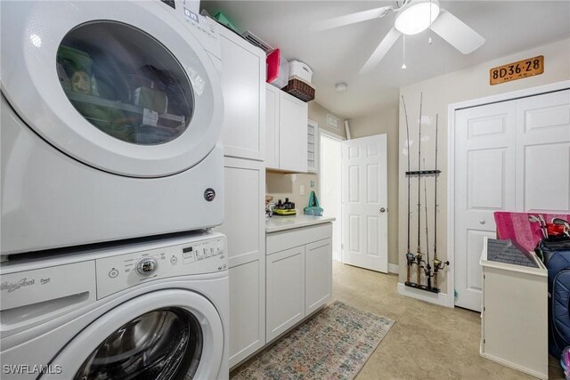 laundry area with cabinets, stacked washer / dryer, and ceiling fan