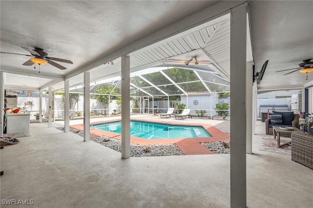 view of swimming pool with ceiling fan, glass enclosure, and a patio