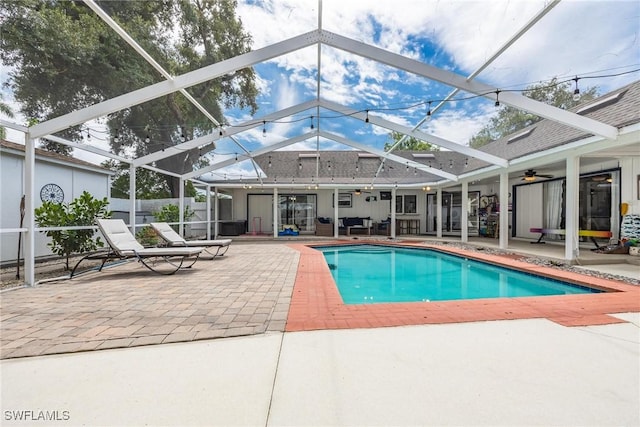 view of pool with glass enclosure, ceiling fan, and a patio