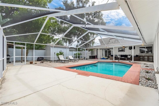 view of pool featuring ceiling fan, a storage shed, glass enclosure, an outdoor hangout area, and a patio