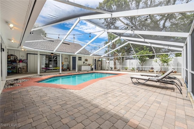 view of pool with glass enclosure and a patio