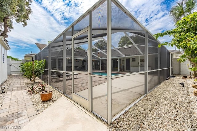 rear view of house featuring a lanai, a patio area, and a fenced in pool