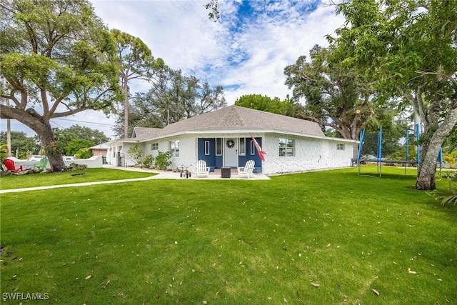 ranch-style house featuring a front lawn and a trampoline