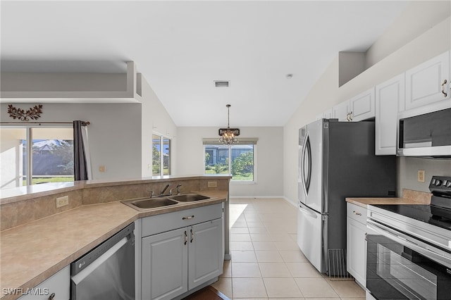 kitchen with appliances with stainless steel finishes, a healthy amount of sunlight, and vaulted ceiling