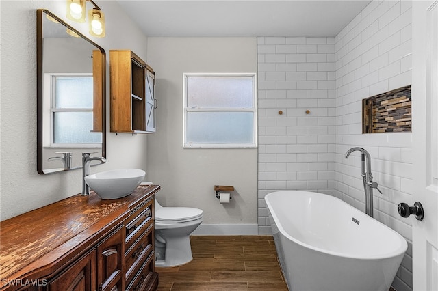 bathroom featuring hardwood / wood-style floors, a tub, vanity, and toilet