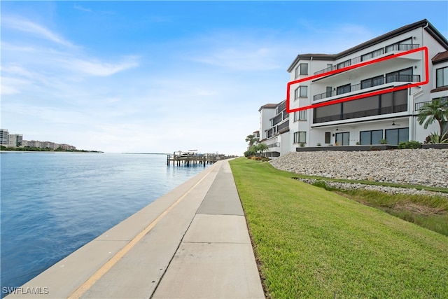 view of dock featuring a water view, a yard, and a balcony