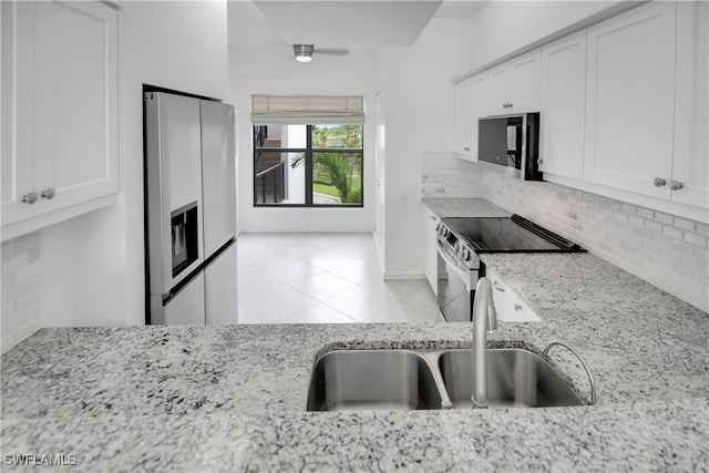 kitchen featuring light stone counters, white cabinets, stainless steel appliances, and sink