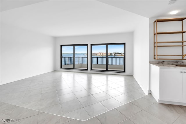 unfurnished living room featuring light tile patterned flooring and sink