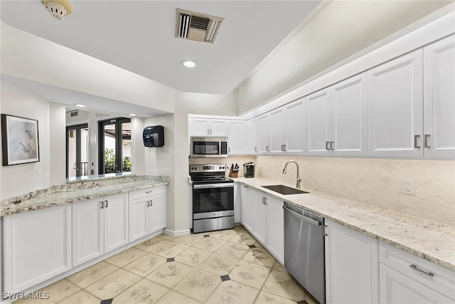 kitchen with appliances with stainless steel finishes, sink, decorative backsplash, and white cabinetry