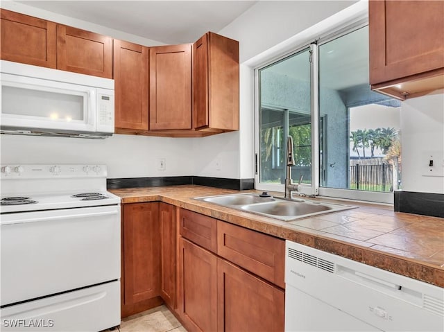 kitchen featuring light tile patterned floors, white appliances, and sink