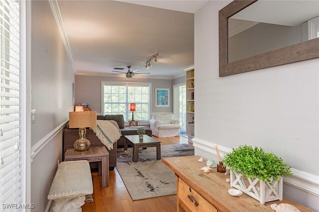 living area featuring hardwood / wood-style flooring, rail lighting, ceiling fan, and ornamental molding