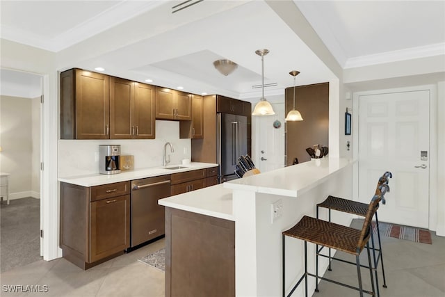 kitchen with light tile patterned flooring, hanging light fixtures, ornamental molding, stainless steel appliances, and a breakfast bar