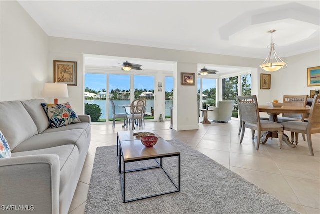 tiled living room with a water view and ceiling fan