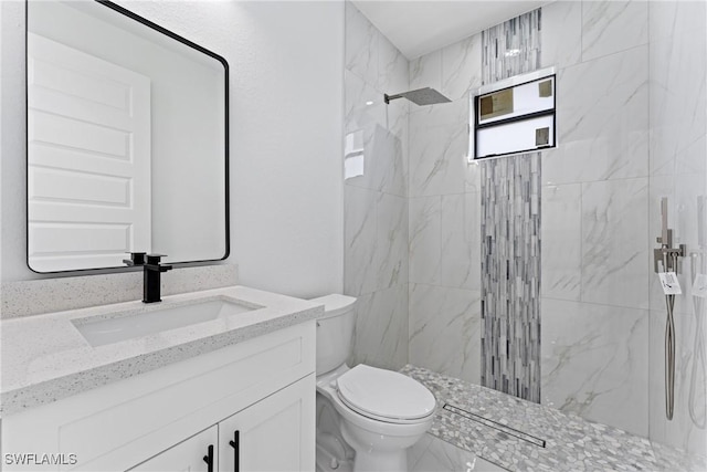 bathroom with tiled shower, vanity, and toilet