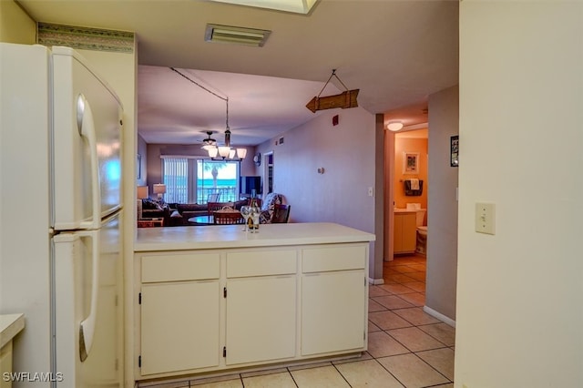 kitchen featuring light tile patterned floors, white cabinetry, a notable chandelier, kitchen peninsula, and white fridge