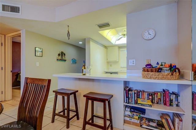 kitchen with a kitchen breakfast bar, kitchen peninsula, and light tile patterned floors