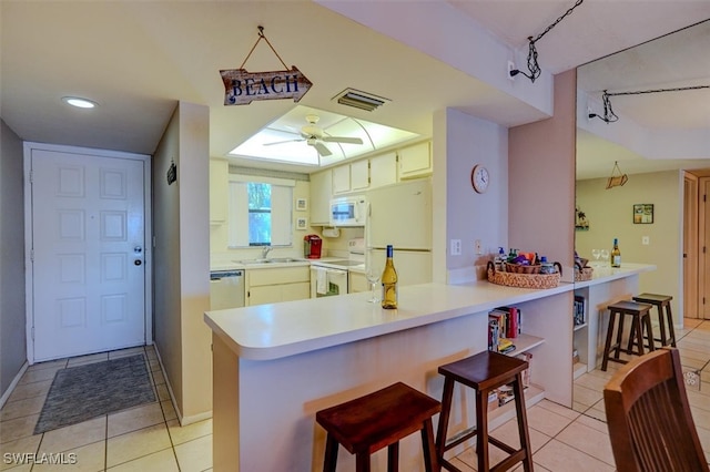 kitchen featuring sink, white appliances, a breakfast bar, ceiling fan, and kitchen peninsula