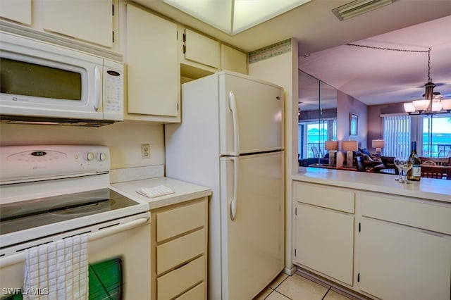 kitchen featuring light tile patterned flooring, an inviting chandelier, hanging light fixtures, white appliances, and cream cabinets