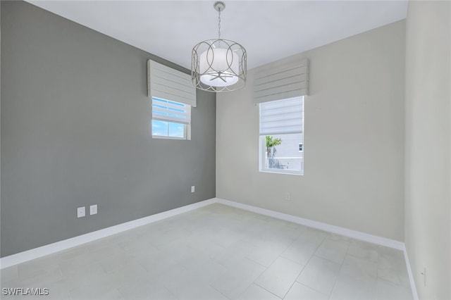 unfurnished room featuring baseboards and an inviting chandelier