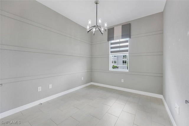 spare room with a chandelier and baseboards