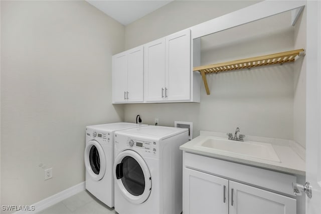 clothes washing area featuring cabinet space, light tile patterned floors, baseboards, washer and clothes dryer, and a sink